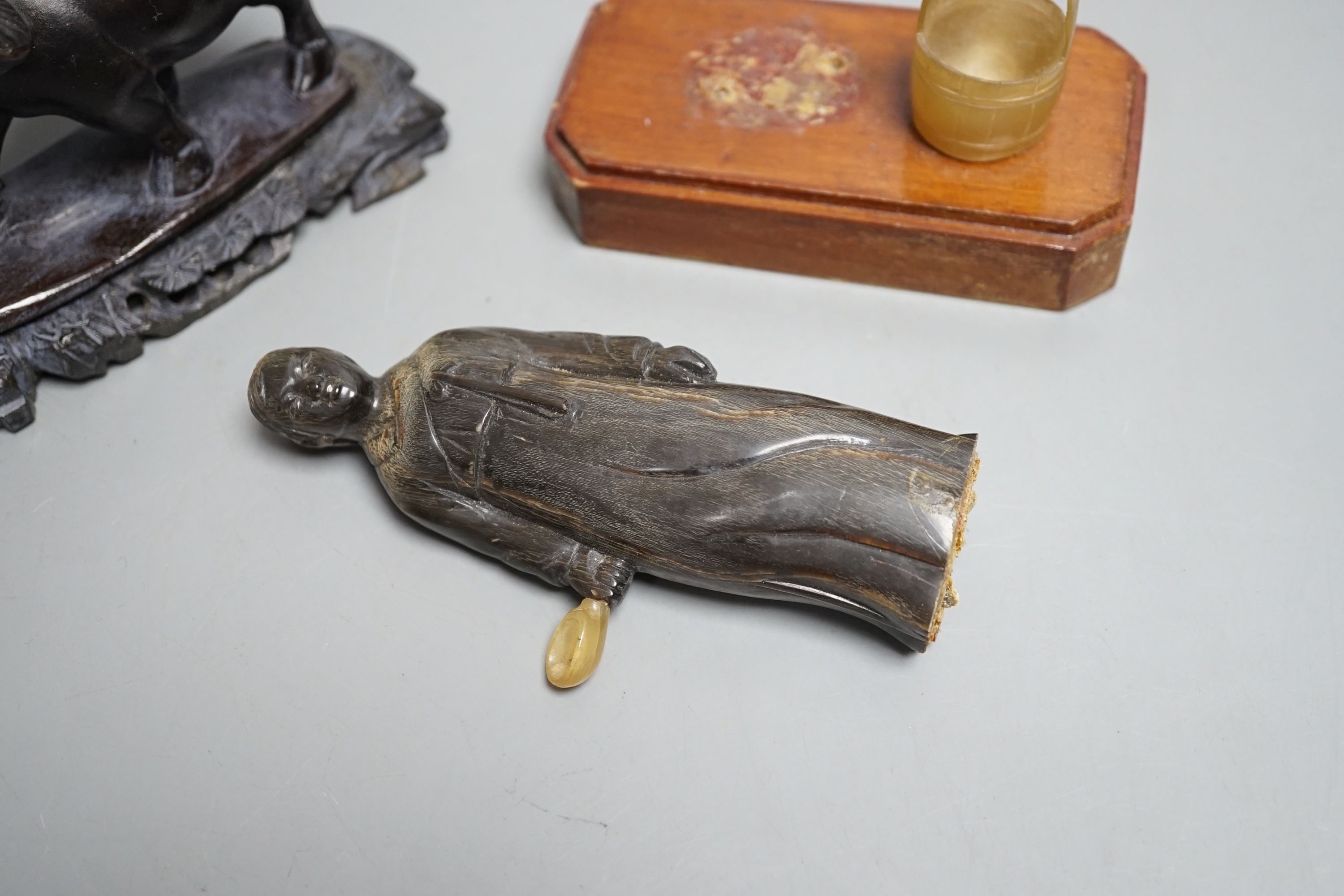 A Chinese horn figure and a carved hardwood figure riding a buffalo,13 cms wide.